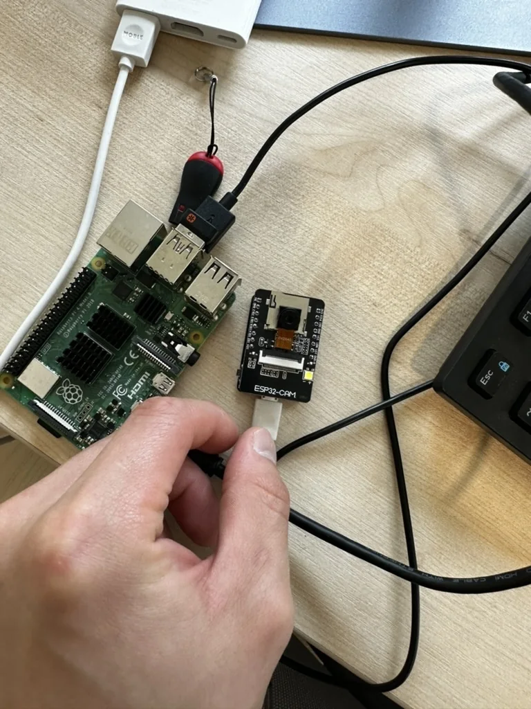 라즈베리파이 옆 ESP32-CAM에 손으로 케이블을 꽂는 장면